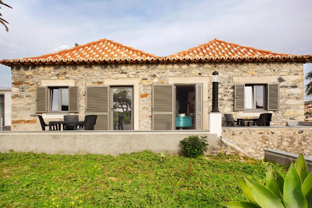 a stone house with shutters and a patio at Quinta Alcaparras in Porto Santo