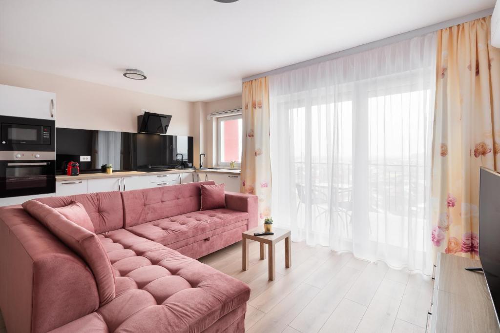 un salon avec un canapé rose devant une fenêtre dans l'établissement Blissful Haven Flats, à Oradea