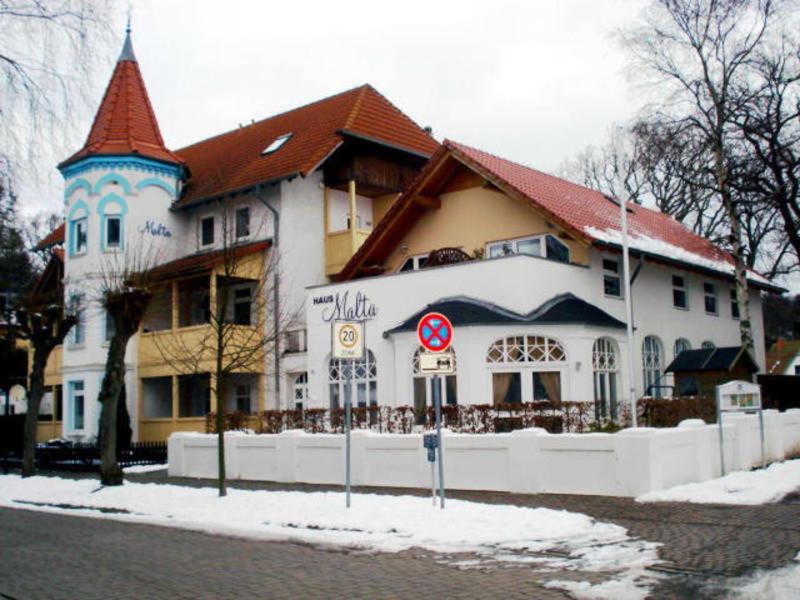 a large white building with a red roof at Haus Malta - Strandstraße in Müritz