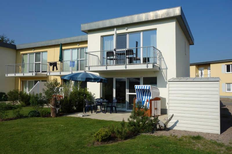 ein Haus mit einem Balkon, einem Tisch und einem Sonnenschirm in der Unterkunft Küstenwald - Ferienwohnung Igelring H in Müritz