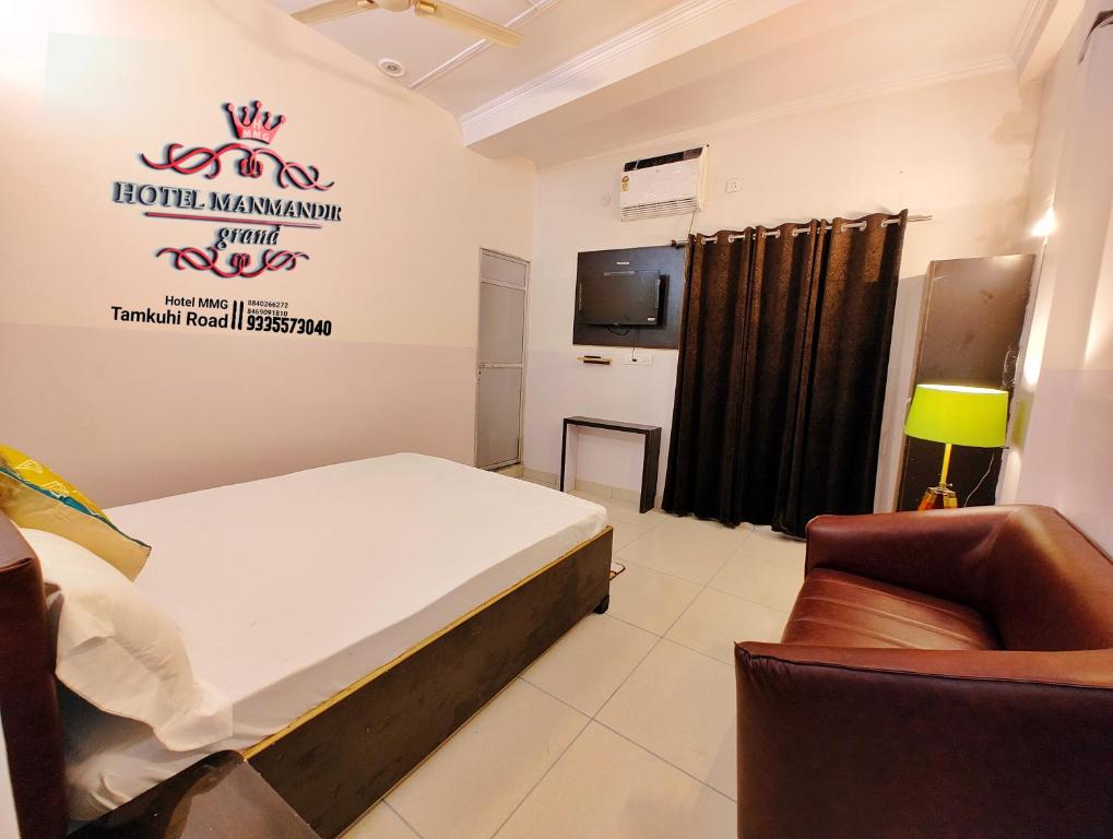 um quarto com uma cama, uma televisão e um sofá em Hotel MMG ManMandir grand 