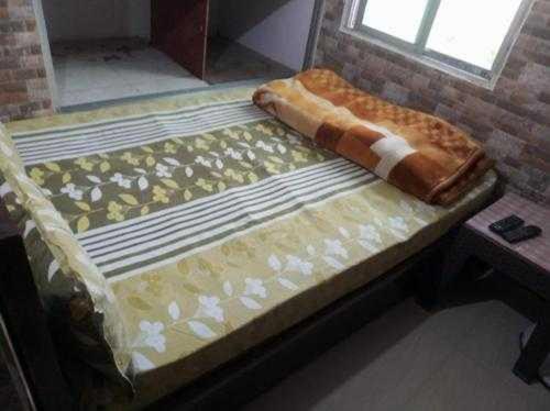 an empty bed in a room with a window at OYO Abhi Hotel in Meerut