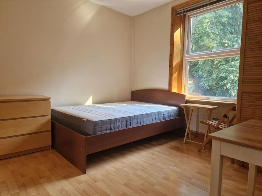 a bedroom with a bed and a desk and a window at Bright studio apartment Highgate in London