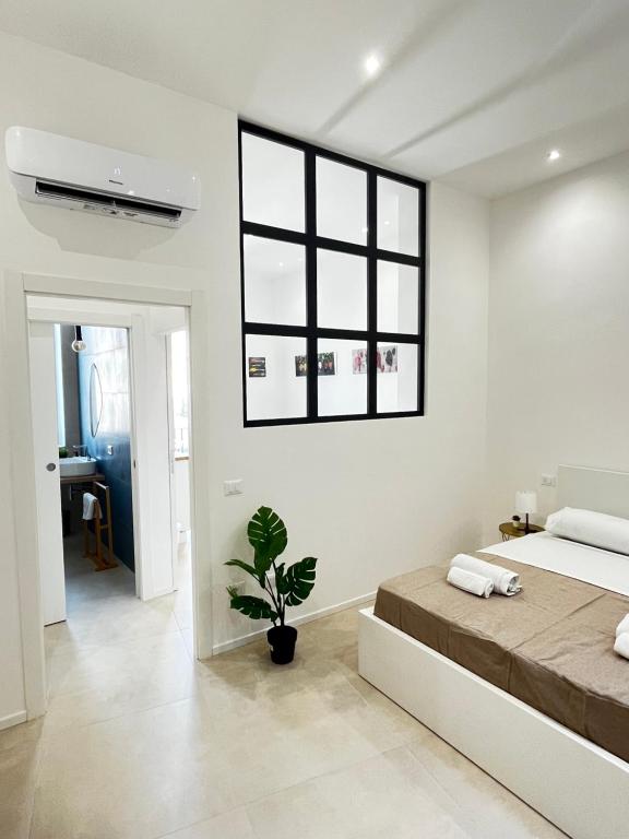 una camera bianca con un grande letto e una pianta di Valguarnera Suites & Apartments a Palermo