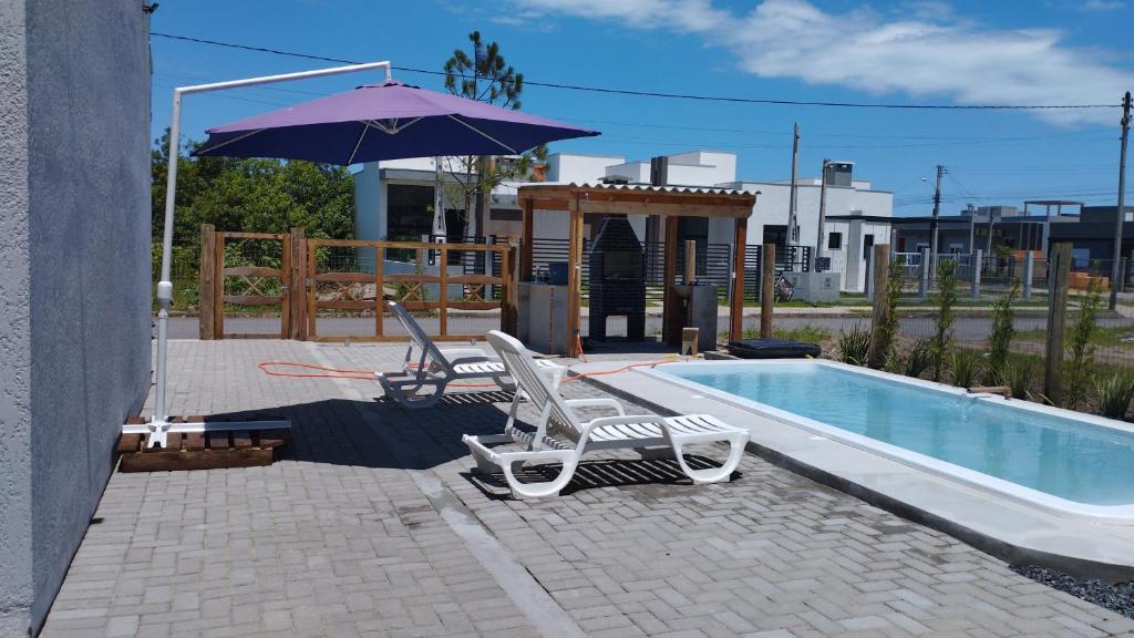 卡龐達卡諾阿的住宿－Morada do bosque，游泳池旁的2把躺椅和遮阳伞