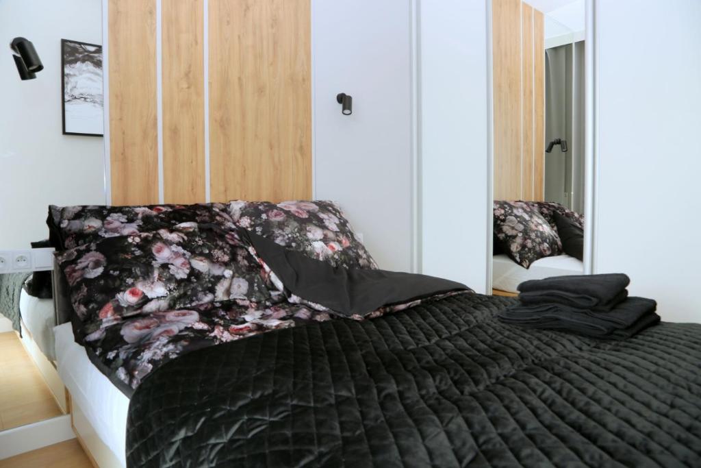 ein Schlafzimmer mit einem Bett mit einer schwarzen Bettdecke in der Unterkunft Narwik Comfort Warszawa Bemowo in Warschau