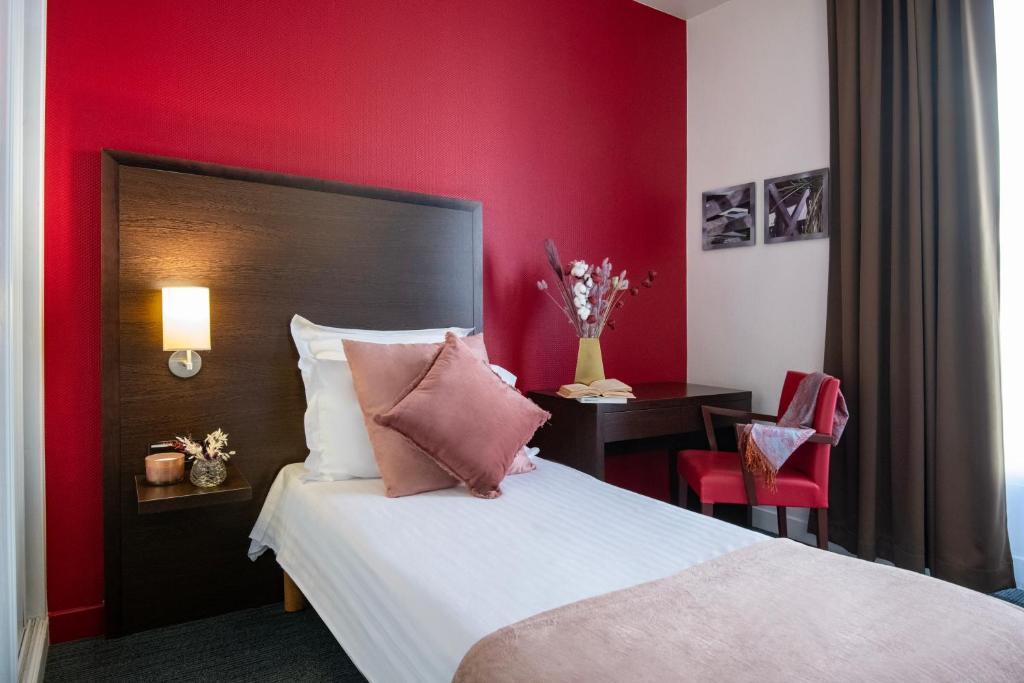 a bedroom with a red wall with a bed and a table at Hôtel Vendôme Menton in Menton