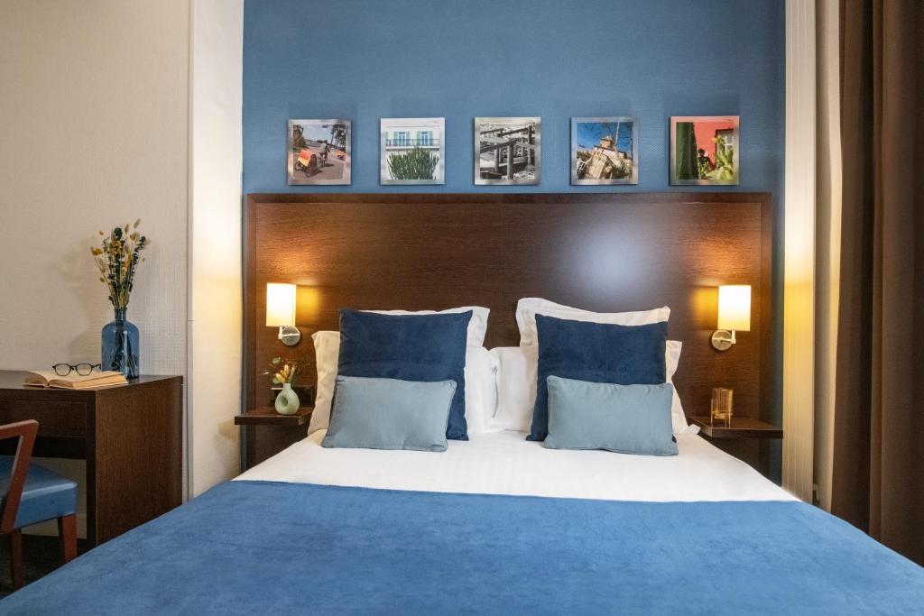 a bedroom with a blue and white bed with blue pillows at Hôtel Vendôme Menton in Menton