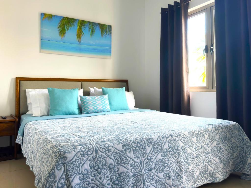 Schlafzimmer mit einem Bett mit blauer und weißer Bettwäsche und einem Fenster in der Unterkunft Residence Le Point Choisy in Pointe aux Cannoniers