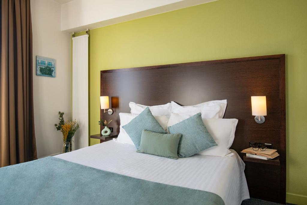 a bedroom with a large bed with blue and white pillows at Hôtel Vendôme Menton in Menton