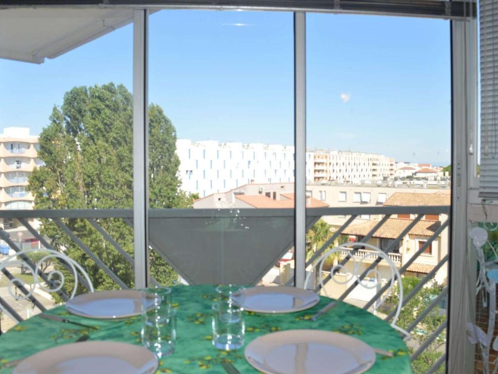 una mesa con platos y vasos en el balcón en Appartement Le Grau-du-Roi, 2 pièces, 4 personnes - FR-1-250-146, en Le Grau-du-Roi