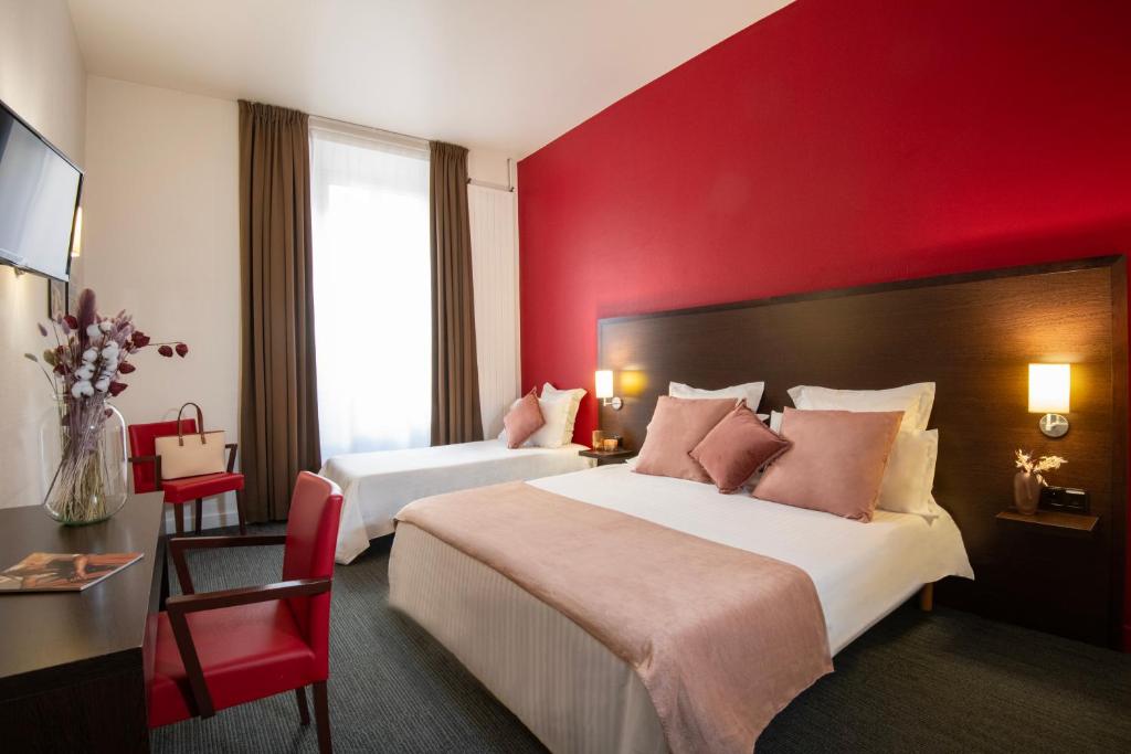 a hotel room with two beds and a red wall at Hôtel Vendôme Menton in Menton