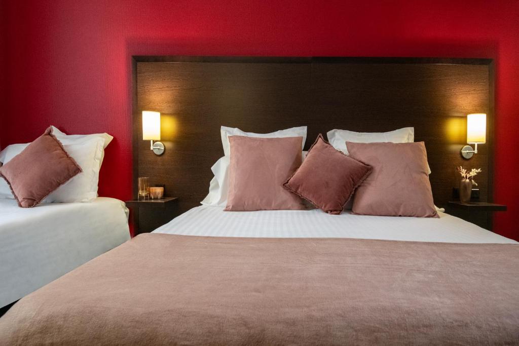 two beds in a hotel room with red walls at Hôtel Vendôme Menton in Menton
