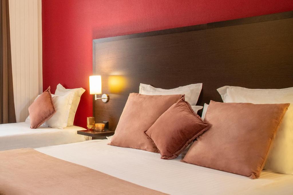 two beds in a hotel room with red walls at Hôtel Vendôme Menton in Menton