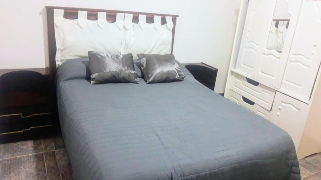 a bed with three pillows on it in a bedroom at Departamento a una cuadra del mar MDP in Mar del Plata