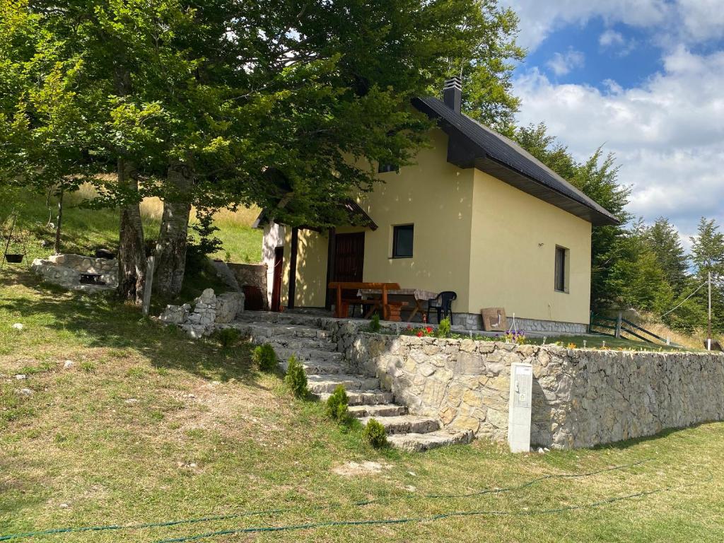 a small house with a stone wall and a tree at Lasica in Žabljak