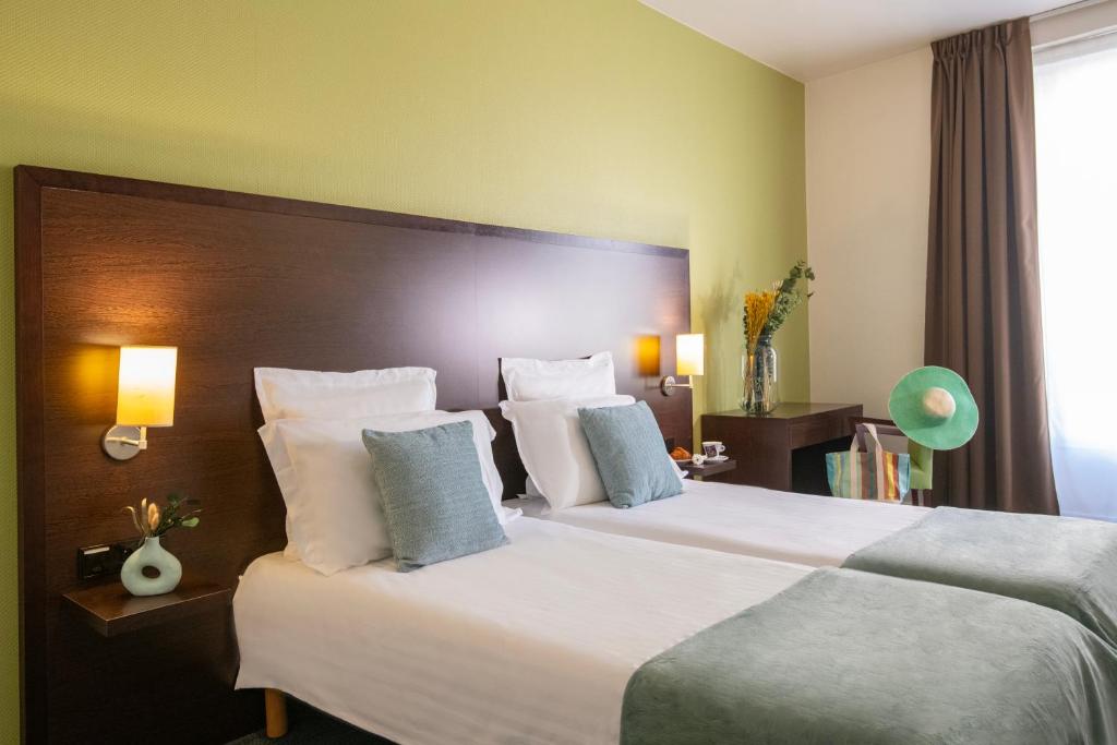 a hotel room with a large bed with white pillows at Hôtel Vendôme Menton in Menton