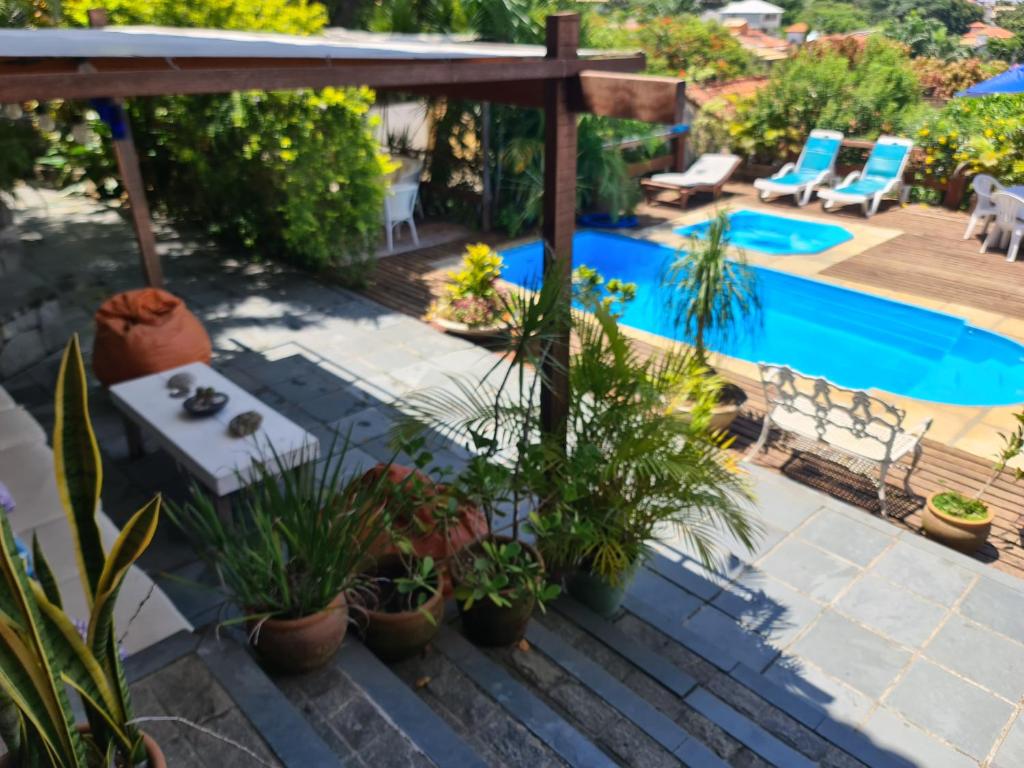 een achtertuin met een zwembad en een terras met planten bij Mira Playa Geribá in Búzios