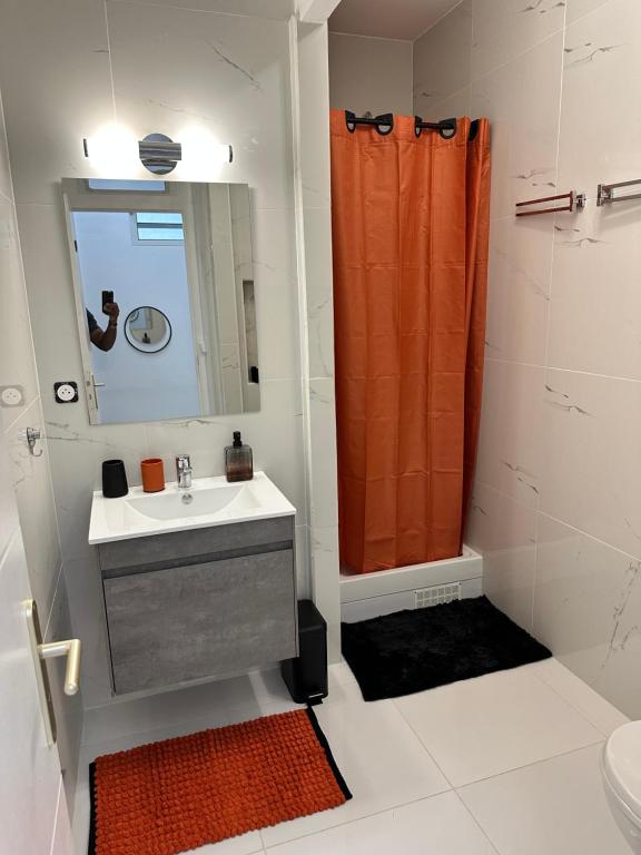 bagno con lavandino e tenda doccia arancione di CYRUS Hôtel -Housse cœur de ville a Pointe-à-Pitre
