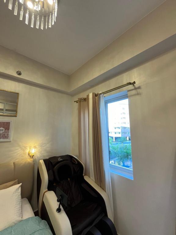 un dormitorio con una maleta sentada en una cama junto a una ventana en PECHO PERFECT SUITE WITH MASSAGE CHAIR, en Cavite