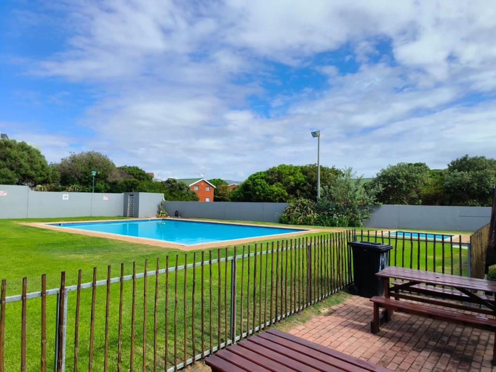 a fence around a swimming pool with a bench at Strictly-Halaal Holiday Home at Meerensee Resort in Fisherhaven