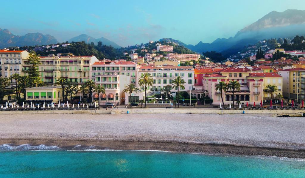 a view of a city with palm trees and buildings at Hôtel Vendôme Menton - Reouverture in Menton