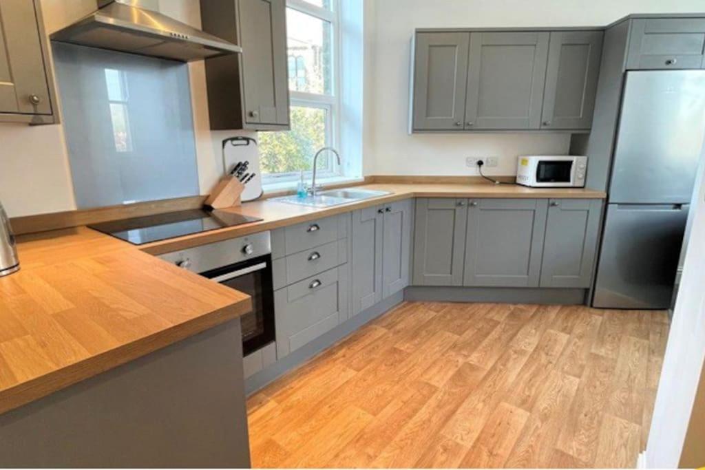 a kitchen with gray cabinets and a wooden floor at CLITHEROE TOWN CENTRE MODERN 2 BED APARTMENT in Clitheroe