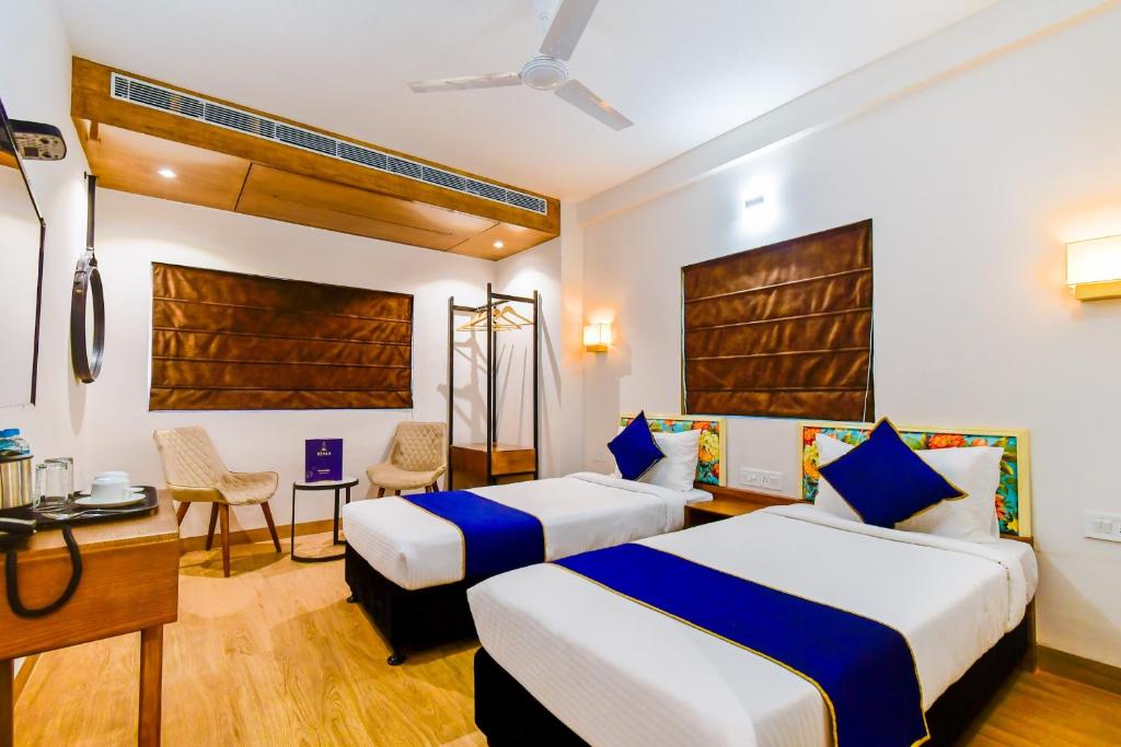 a hotel room with two beds and a desk at Revaa Hotels in kolkata