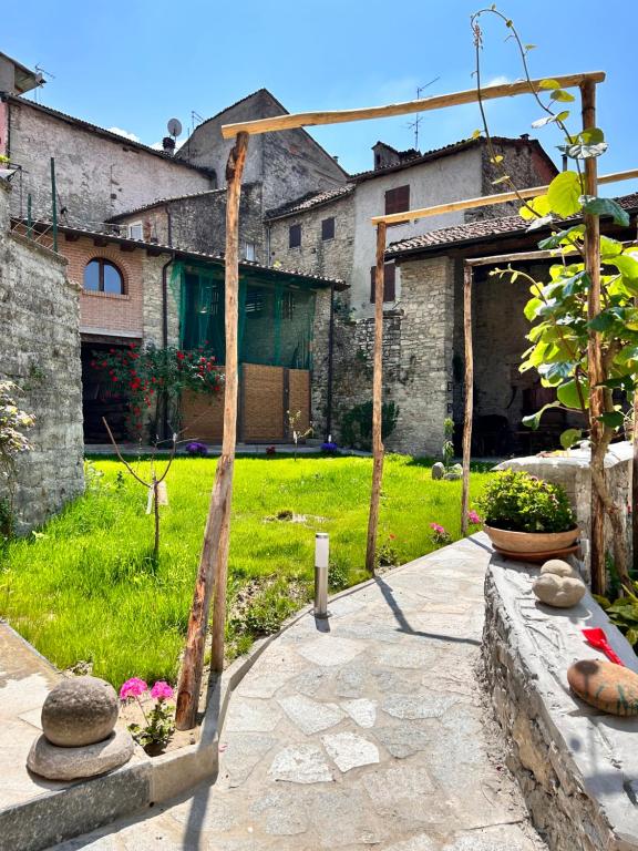 a garden with a wooden arch in front of a building at Guest House il Il Podestà in Garbagna