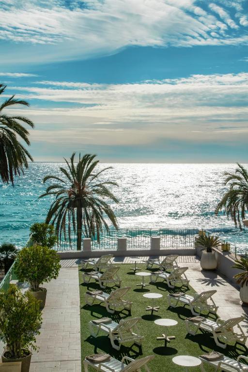 a view of the ocean from a resort with tables and chairs at Hôtel Vendôme Menton in Menton