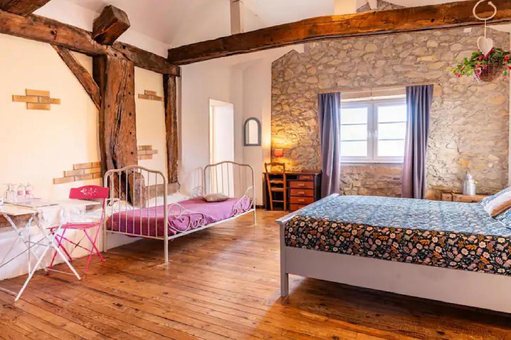 1 dormitorio con 2 camas y pared de piedra en Les Ecuries du SEQUE, en Saint-Martin-de-Seignanx