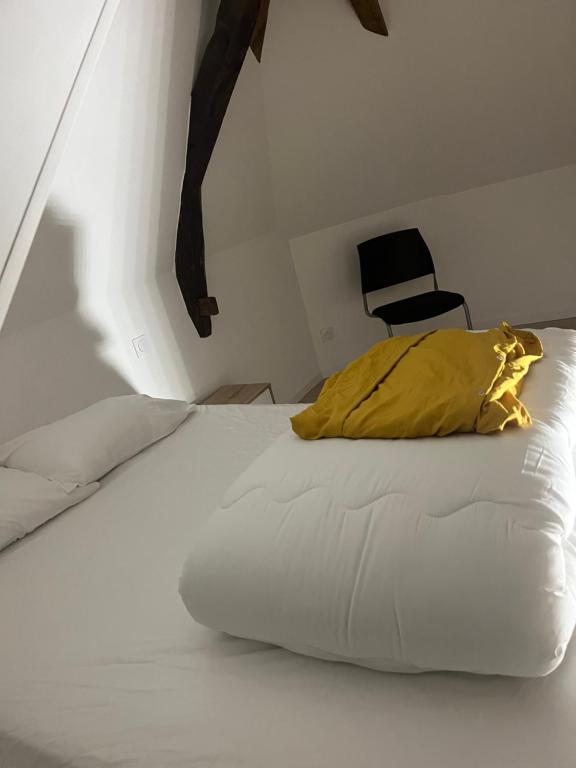 1 cama con almohada amarilla y silla negra en Appart T3 neuf à 15 min d’Angers, en Corné