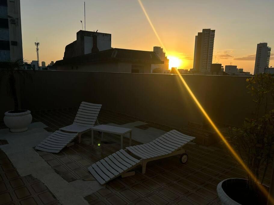 two chairs and a table on a rooftop with the sunset at TOP 3 Quartos - Cobertura Praia da Enseada Guarujá 650m do Mar in Guarujá