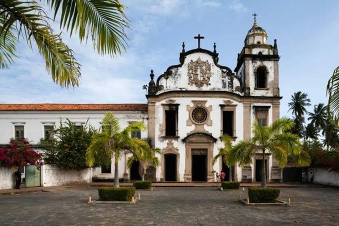 un vecchio edificio con una chiesa con palme di fronte di Casa Carnaval Olinda a Olinda