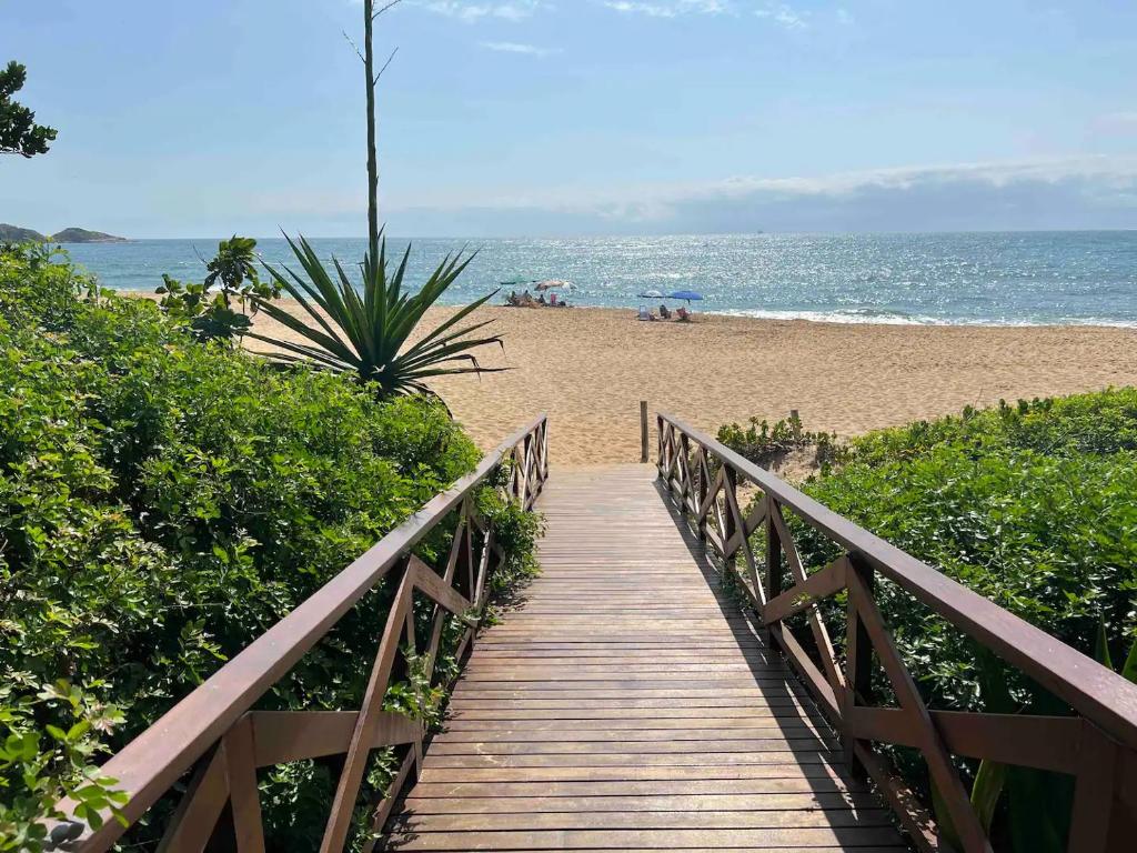 a wooden boardwalk leading to a beach with the ocean at Casa pé na areia em praia paradisíaca com piscina frente mar in Balneário Camboriú