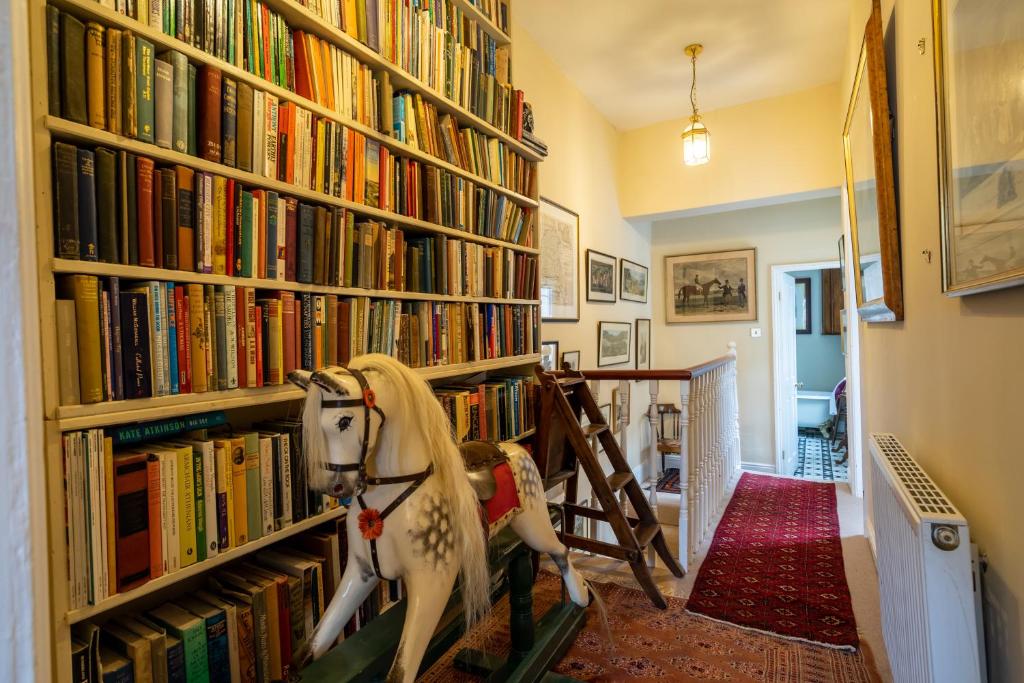 eine Bibliothek mit einem Schaukelpferd vor einem Bücherregal in der Unterkunft The Victorian House in York