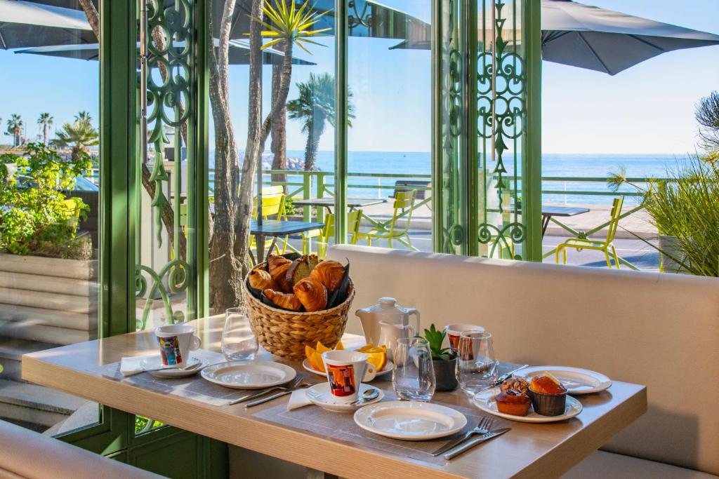 a table with food and a basket of bread at Hôtel Vendôme Menton in Menton