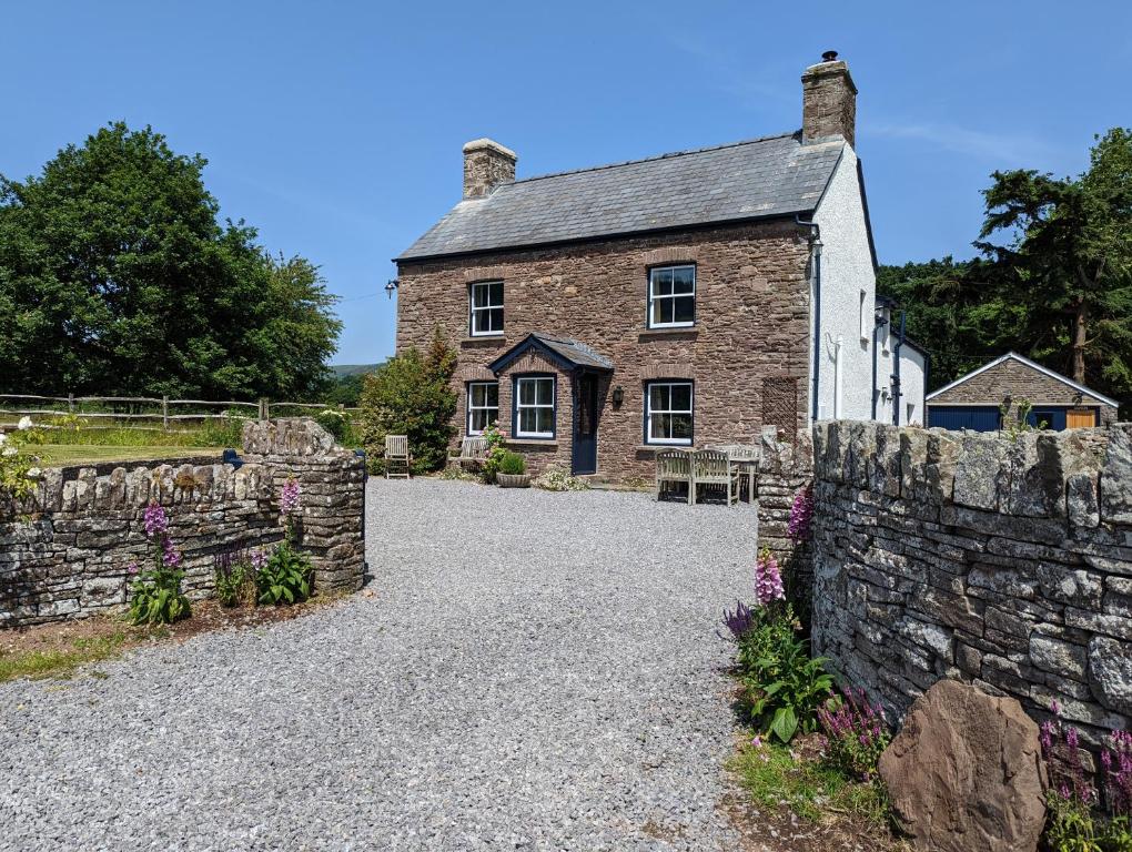 an old brick house with a stone wall at Ty Sinsir in Crickhowell