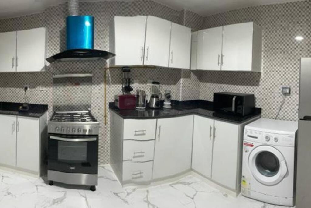 a kitchen with white cabinets and a stove and a washer at Private room available in Arjan. in Dubai