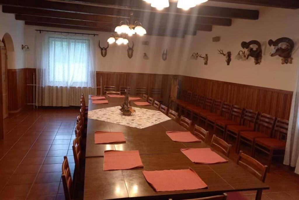 una sala de conferencias con una larga mesa de madera y sillas en Erdei vadászház medencével, jakuzzival (partyház), en Pusztavám