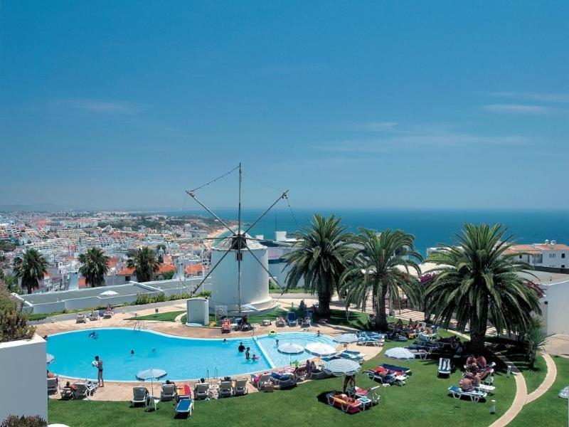 a pool with a windmill in the middle of a resort at The Albufeira Concierge - Moinho Pool & Gardens in Albufeira