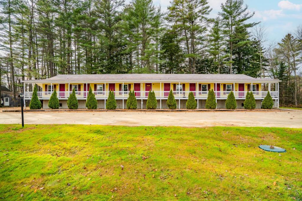 un gran edificio blanco con puertas rojas y patio en The Inn at the Rostay, en Bethel