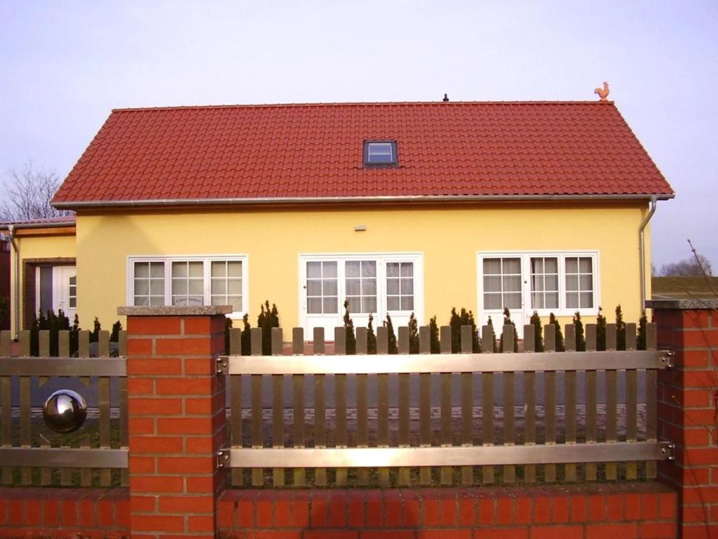 una casa amarilla con una valla y un techo rojo en Apartment am Elberadweg, en Damnatz