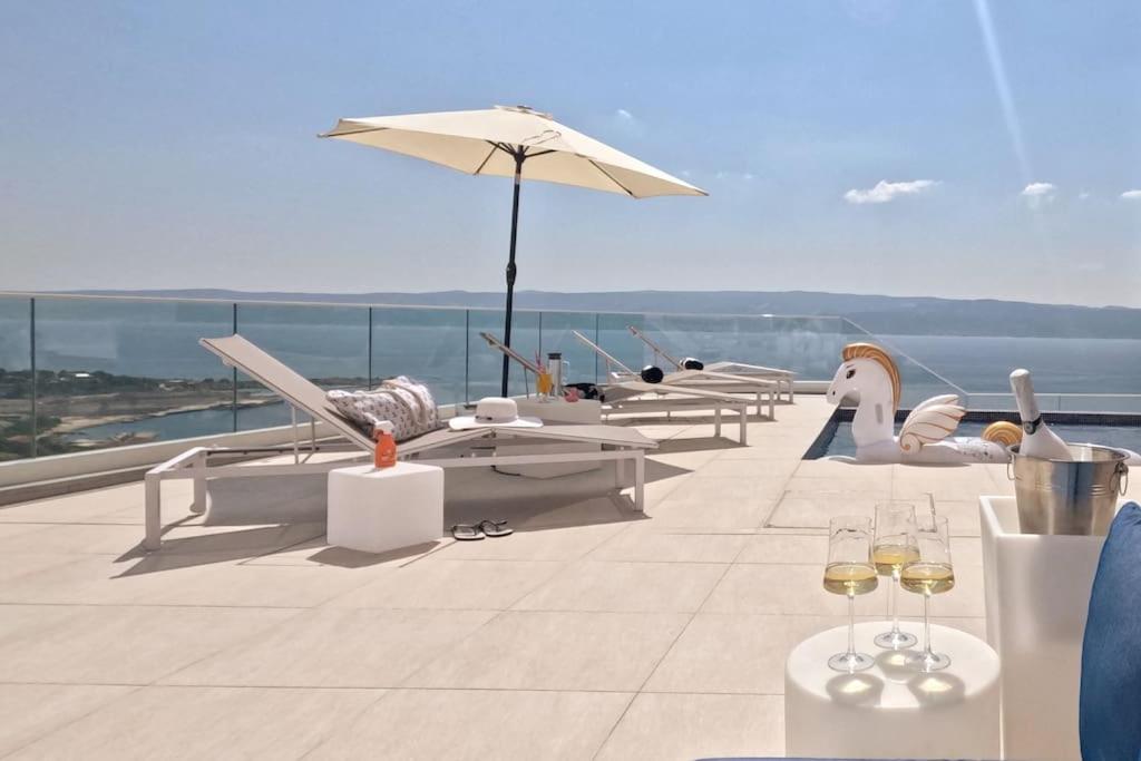 een rij stoelen en een paraplu op een dak bij New! Luxury Boutique Villa Fay, heated Pool, Jacuzzi, Seaview near Split and Omis in Dugi Rat
