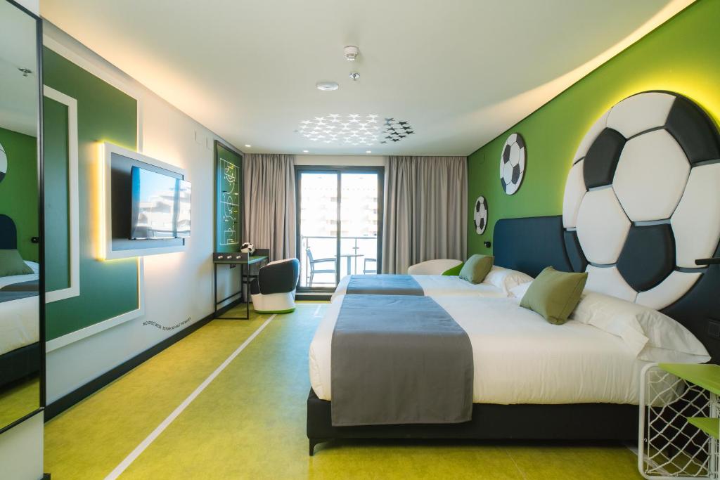 1 dormitorio con 1 cama grande y una pelota de fútbol en la pared en Hotel Magic Sports 4, en Oropesa del Mar