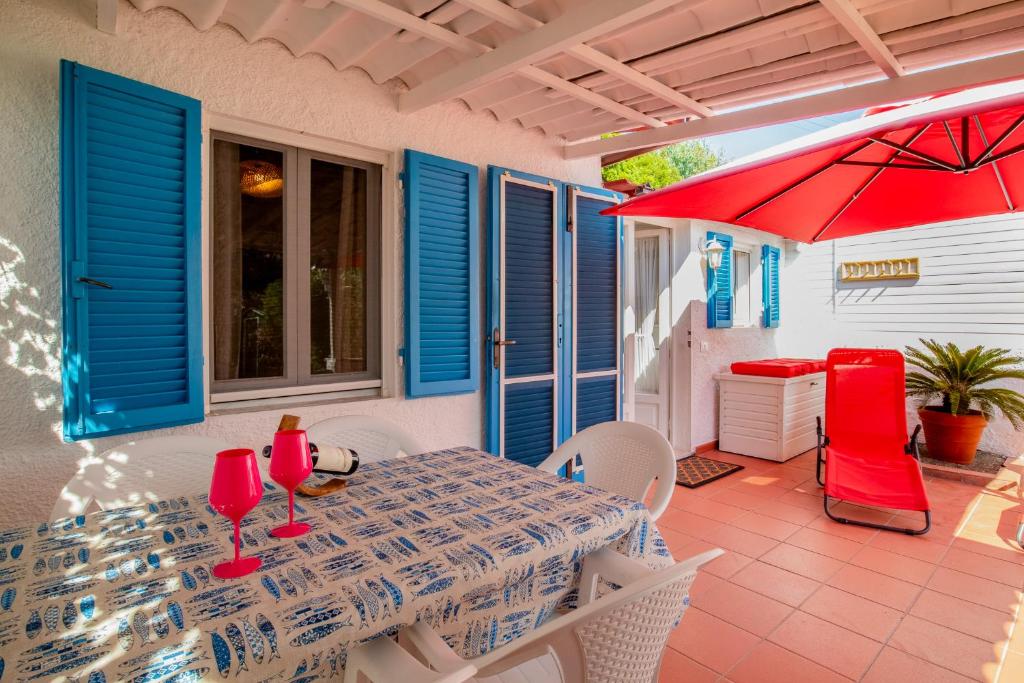 a patio with a table and chairs and a red umbrella at Casa Innamorati in Capoliveri