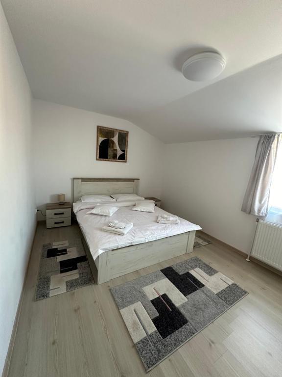 a white bedroom with a bed and a rug at Jokai Apartments Nr7, code entry in Sfântu-Gheorghe