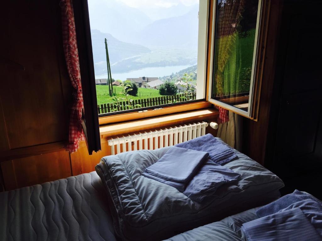 Bett in einem Zimmer mit einem großen Fenster in der Unterkunft AmdenLodge - Berg Chalet in Amden am Walenssee - Event, Seminar, Ferienlager in Amden