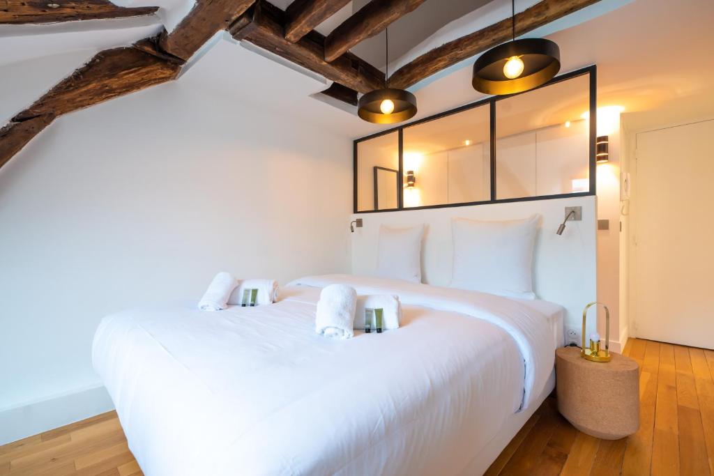 - une chambre avec un grand lit blanc et du parquet dans l'établissement Rooftops of Paris l Opéra - Madeleine, à Paris