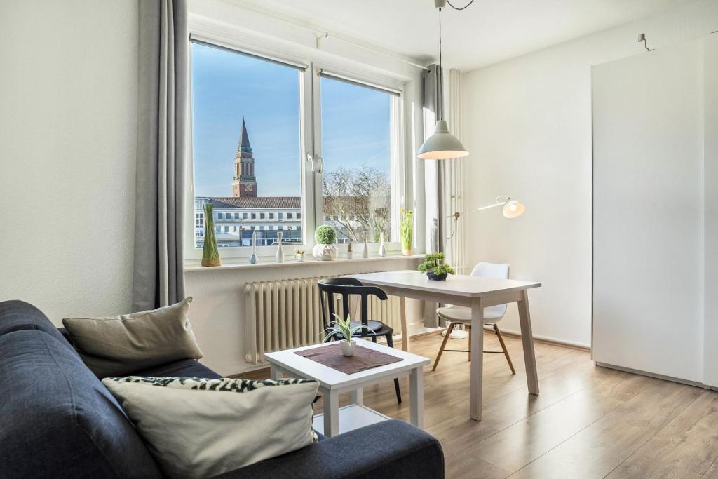 ein Wohnzimmer mit einem Sofa, einem Tisch und einem Fenster in der Unterkunft Ferienwohnung Kieler Altstadt in Kiel